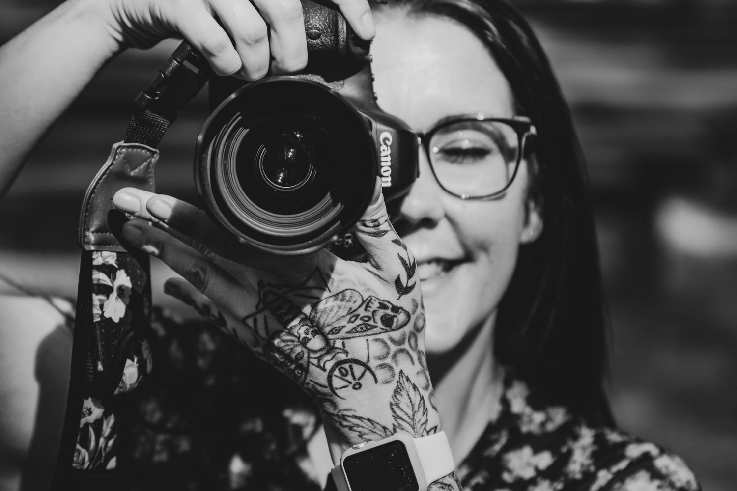 Close-up portrait of photographer holding professional camera in black and white.
