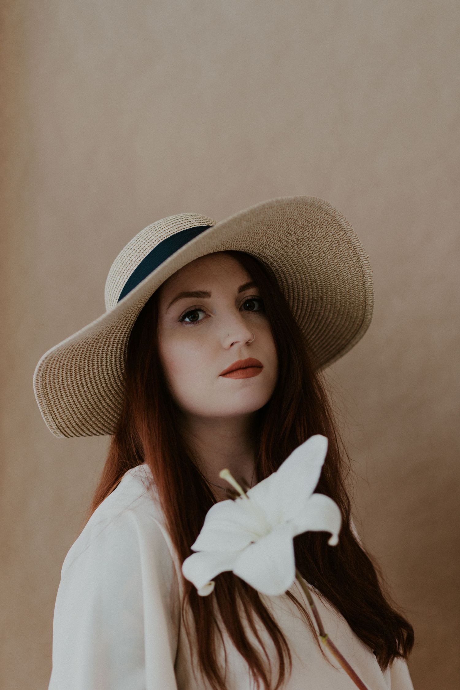 Portrait with a wide-brim straw hat and white butterfly decoration.