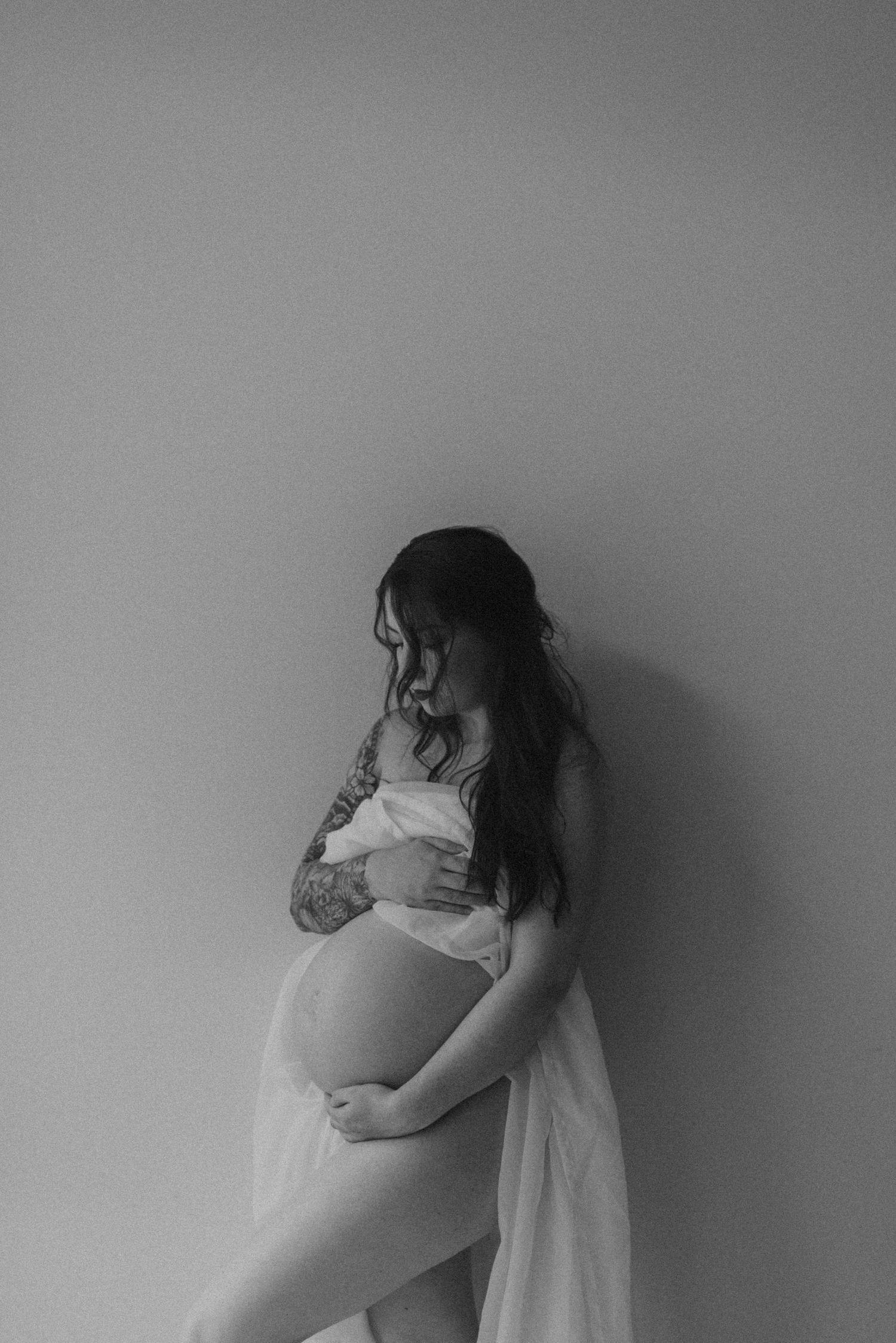Black and white maternity photo showing a silhouette against a plain wall.