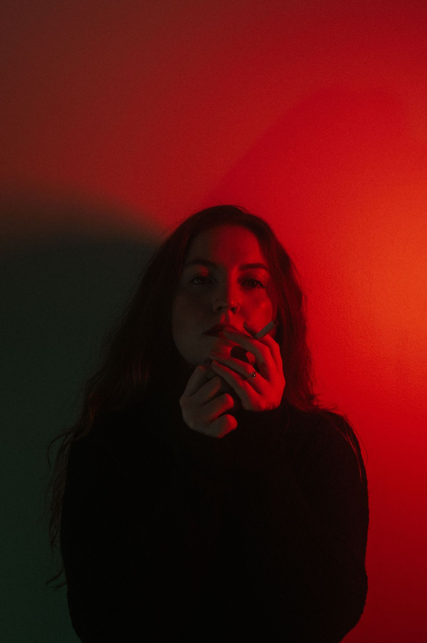 Dramatic portrait in red and green lighting creating mysterious mood.