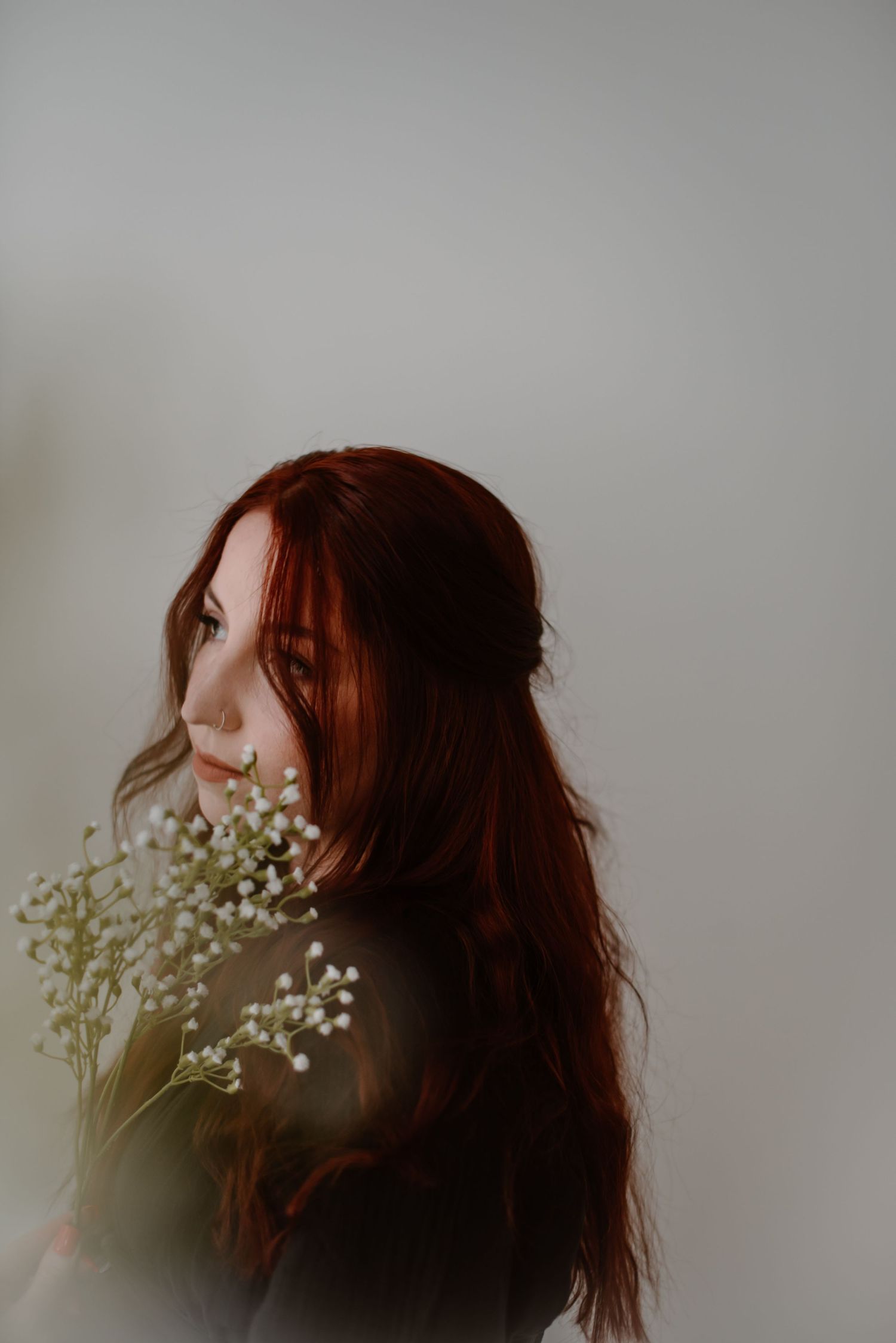 Artistic portrait with baby's breath flowers against a minimalist background.