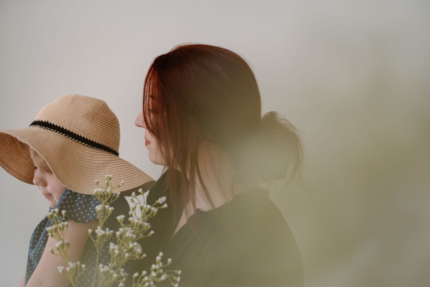 Soft focus image of figures with a straw hat among delicate flowers.