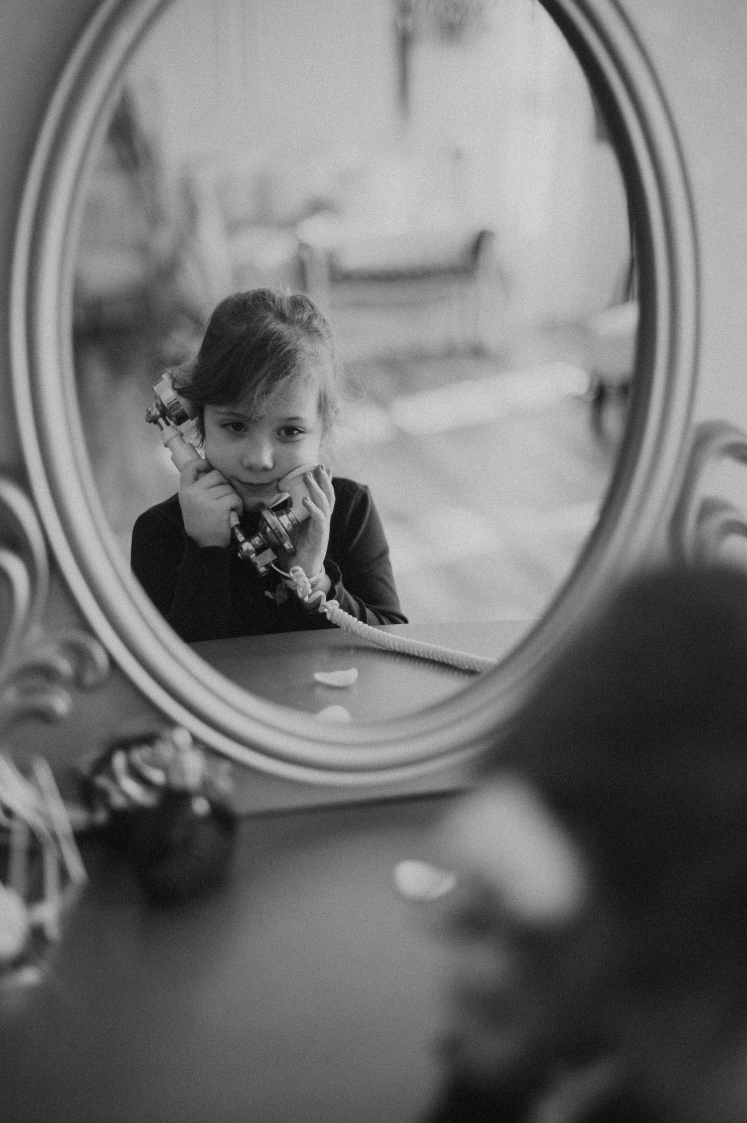 Black and white reflection in an ornate oval mirror creating a dreamy vintage atmosphere.
