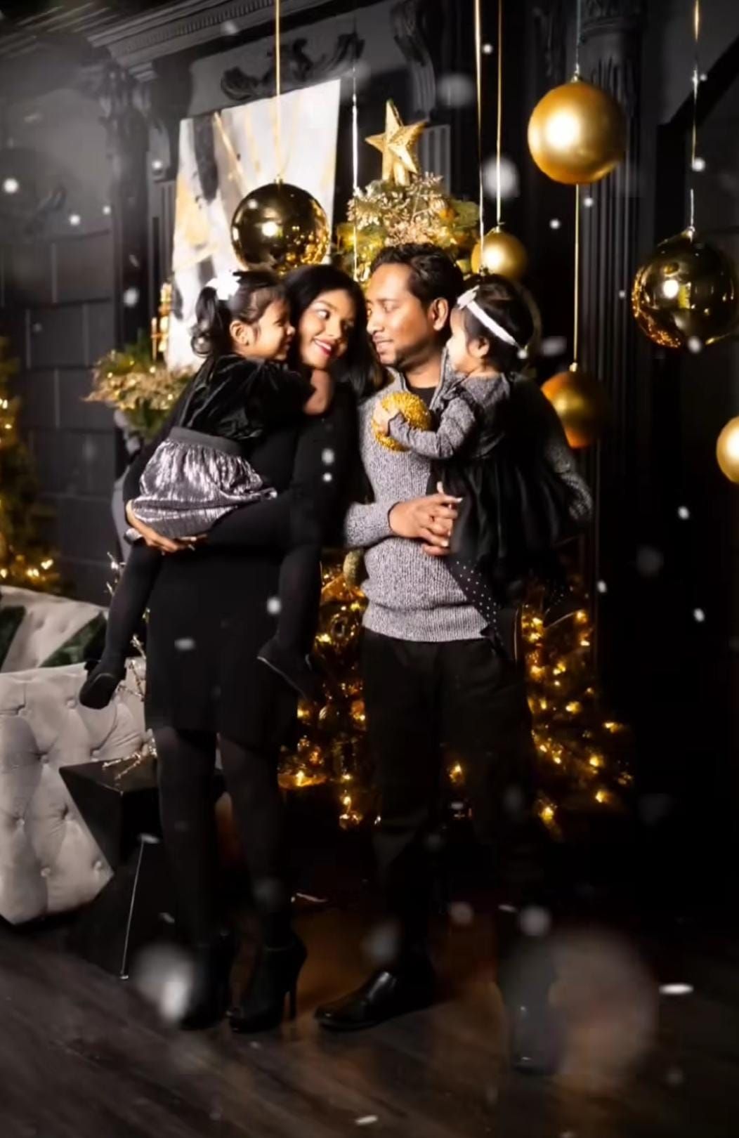 Family holiday portrait with gold ornaments and festive lighting decorations.