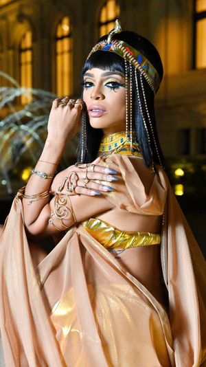Close-up portrait in ornate Egyptian headdress with beaded details and metallic accents.