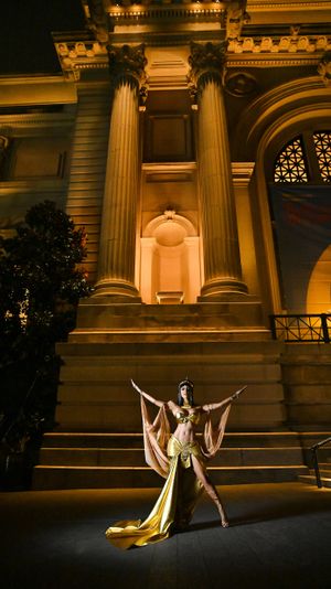Egyptian-inspired dancer pose against illuminated classical building columns at night.
