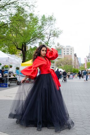 Dramatic red top and black tulle skirt ensemble in urban park setting.