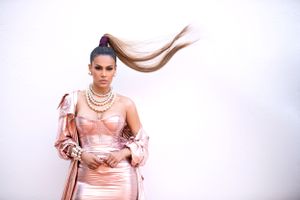 High fashion portrait in pink satin gown with sleek pulled-back hair against white background.