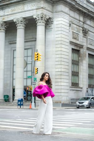 Elegant outfit with magenta statement sleeve top against classical bank building architecture.