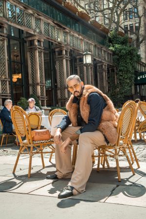 Casual streetwear outfit with fur vest at outdoor cafe with traditional rattan chairs.