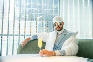 Modern business attire with white jacket and sunglasses in contemporary lounge setting.