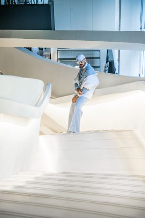 Fashion portrait in all-white modern architectural space with geometric design elements.