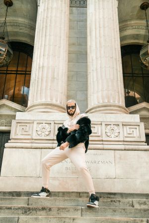 Dynamic pose on stone steps between classic columns of historic building.