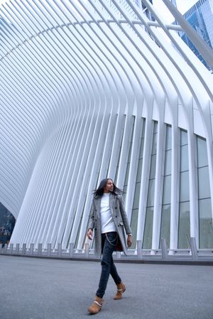 Walking pose beneath striking white ribbed architectural structure.