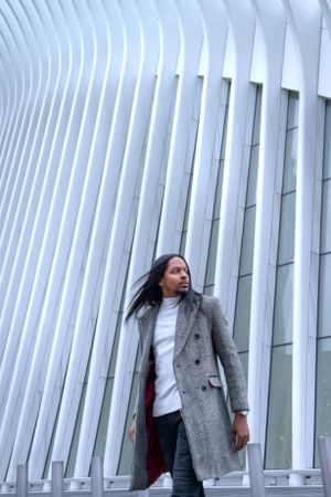 Dramatic fashion pose against modern white architectural ribs background.