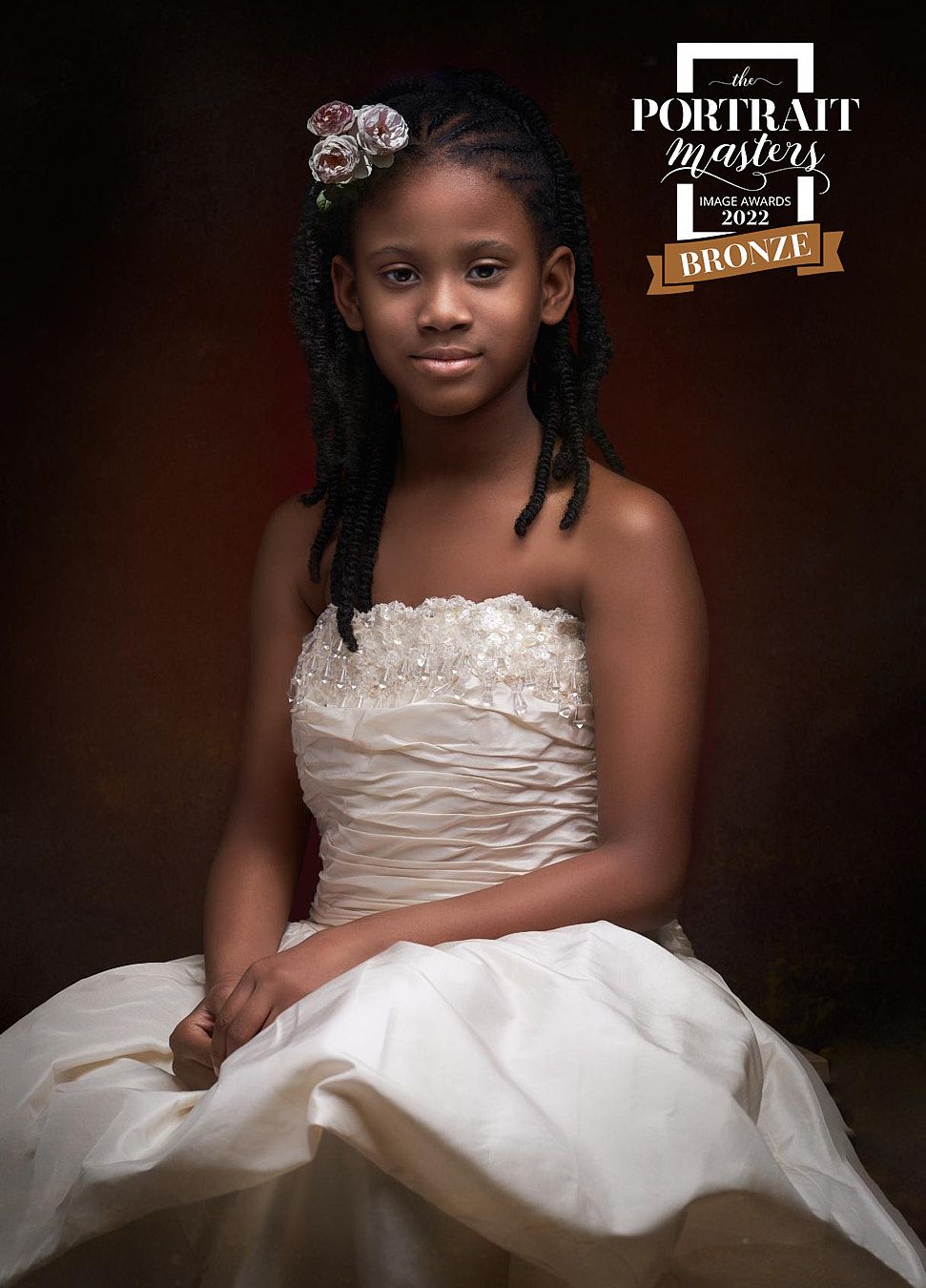 Young girl in white gown with floral hair accessory, Portrait Masters 2022 Bronze award portrait.