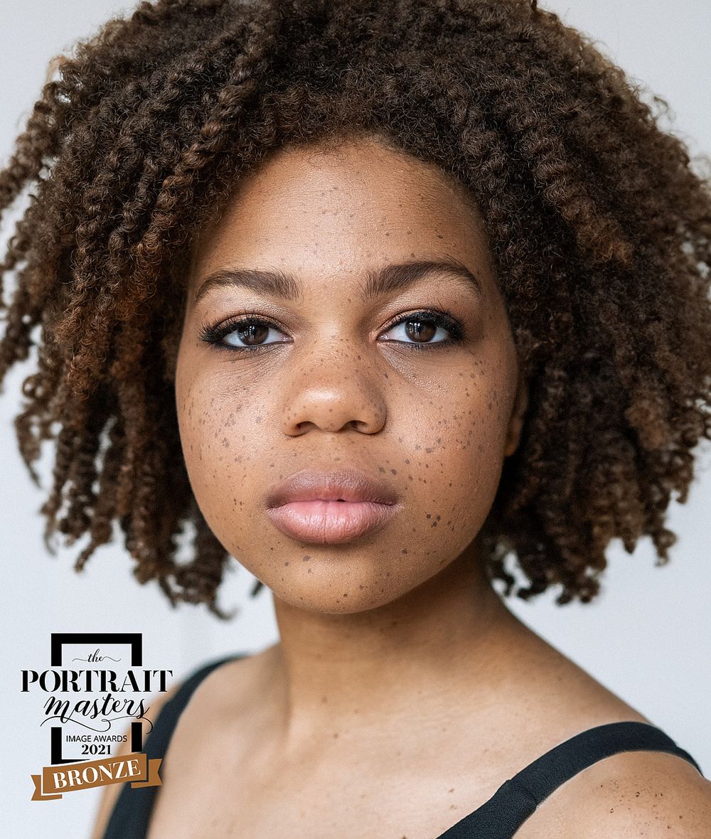 Close-up portrait of young woman with natural afro and freckles, Portrait Masters 2021 Bronze award winner.