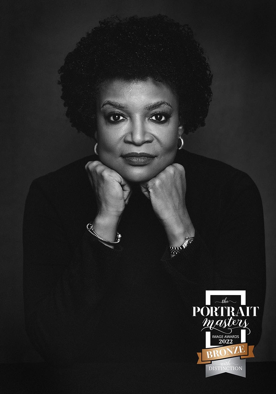 Black and white portrait of mature woman with hands clasped, Portrait Masters 2022 Bronze Distinction.