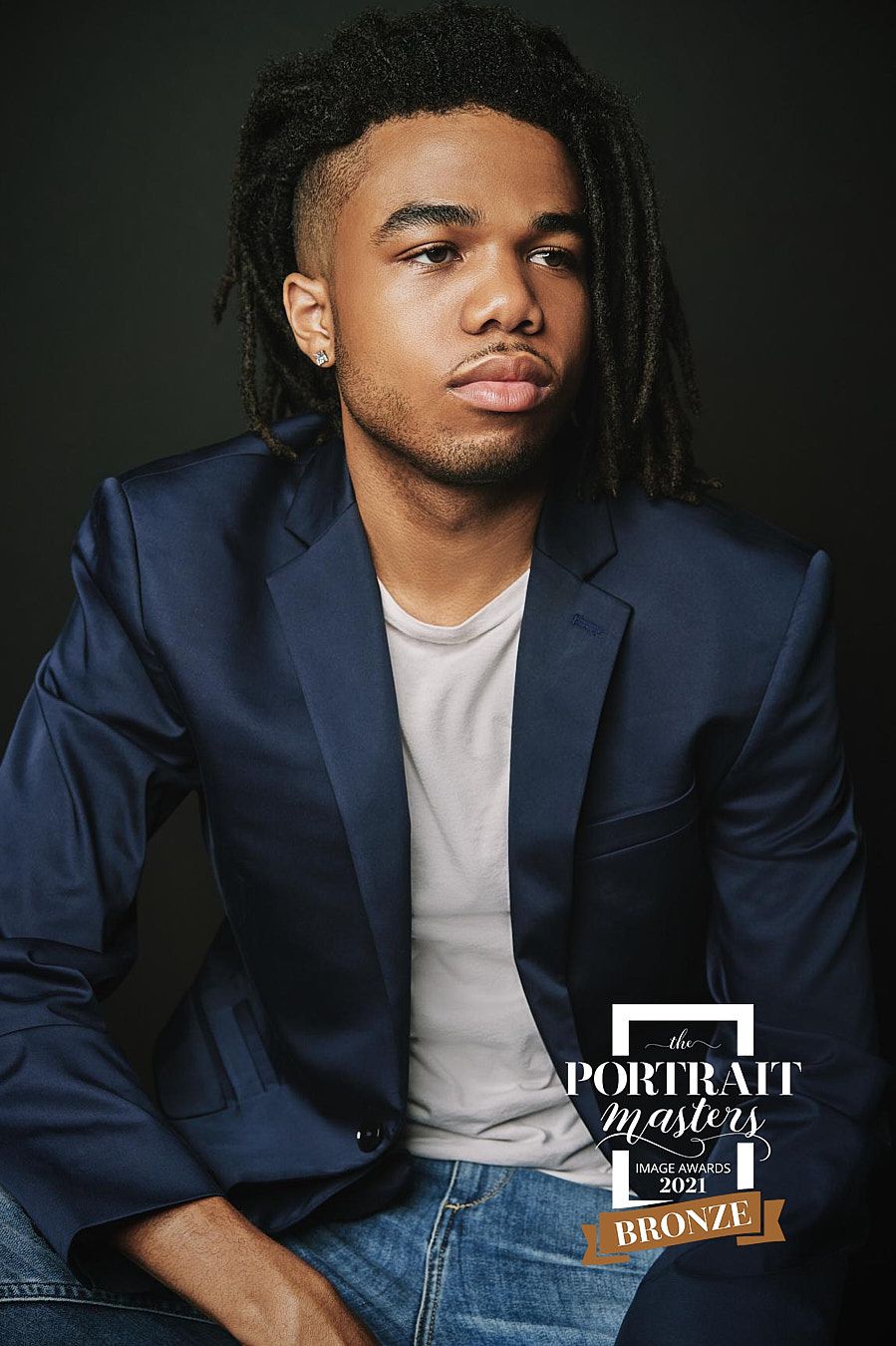 Young man with locs wearing navy blazer and white tee, Portrait Masters 2021 Bronze award portrait.