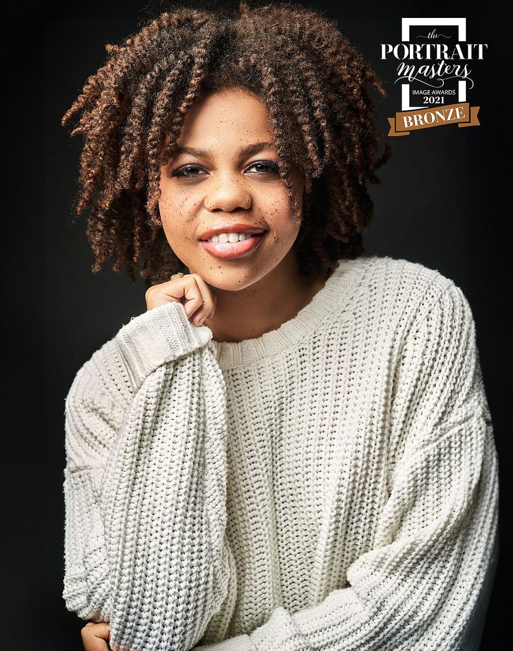 Smiling woman with natural hair in white knit sweater, Portrait Masters 2021 Bronze award portrait.