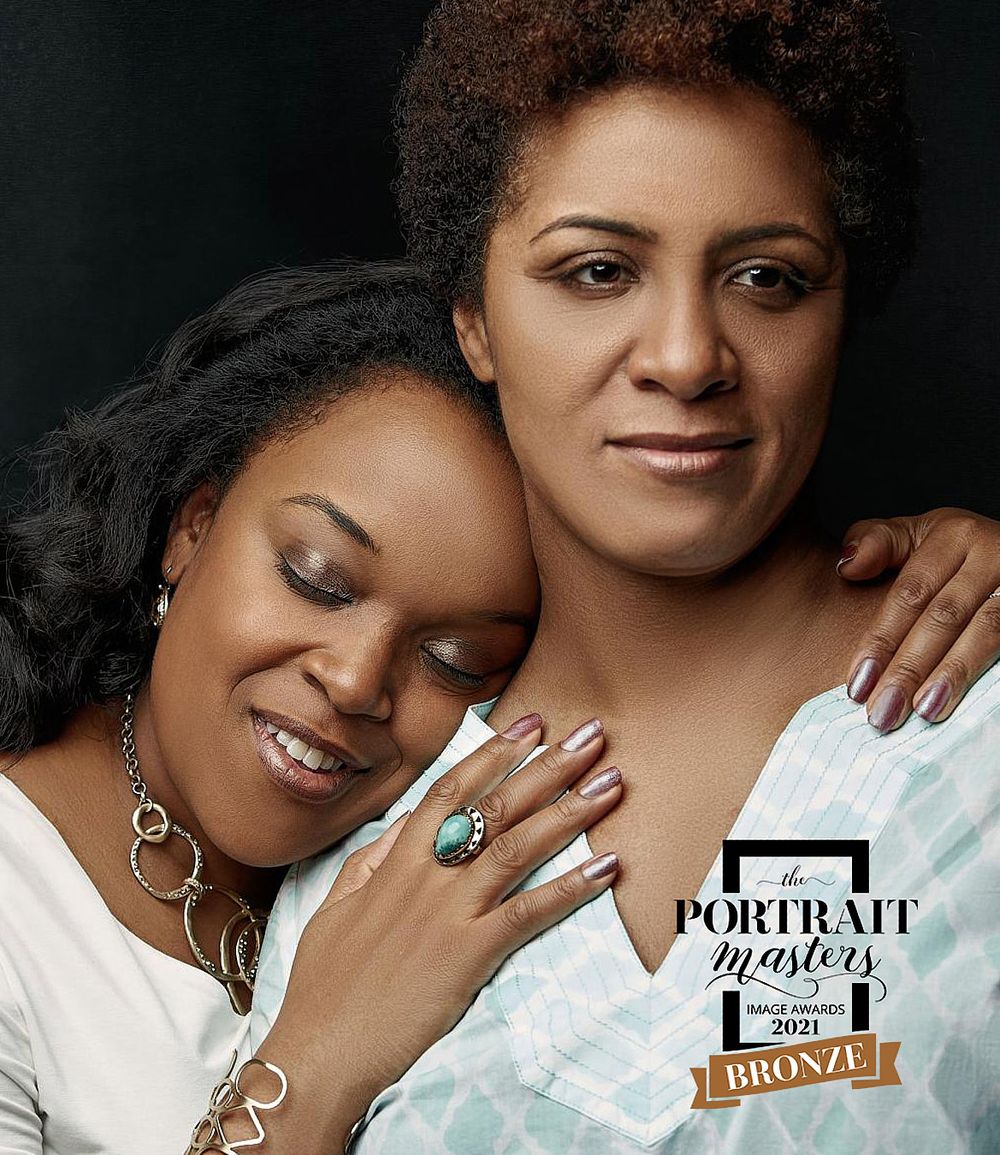 Two women smiling and embracing warmly, Portrait Masters 2021 Bronze award portrait photography.