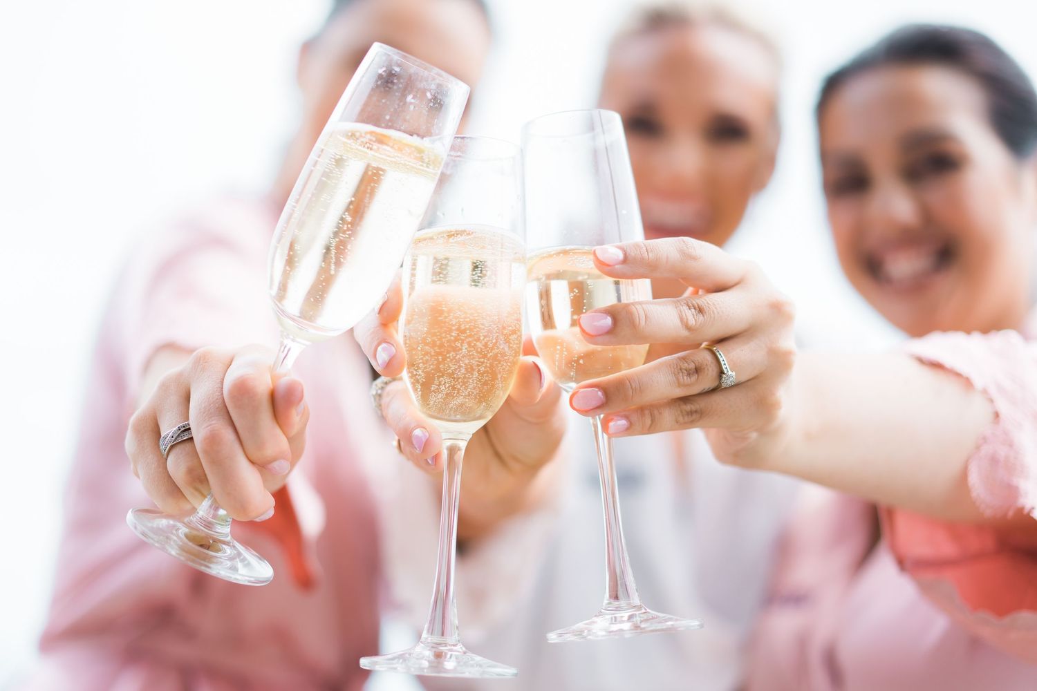 smiling bridesmaids raising glass to cheers with bubbles on wedding day for auckland wedding photographer