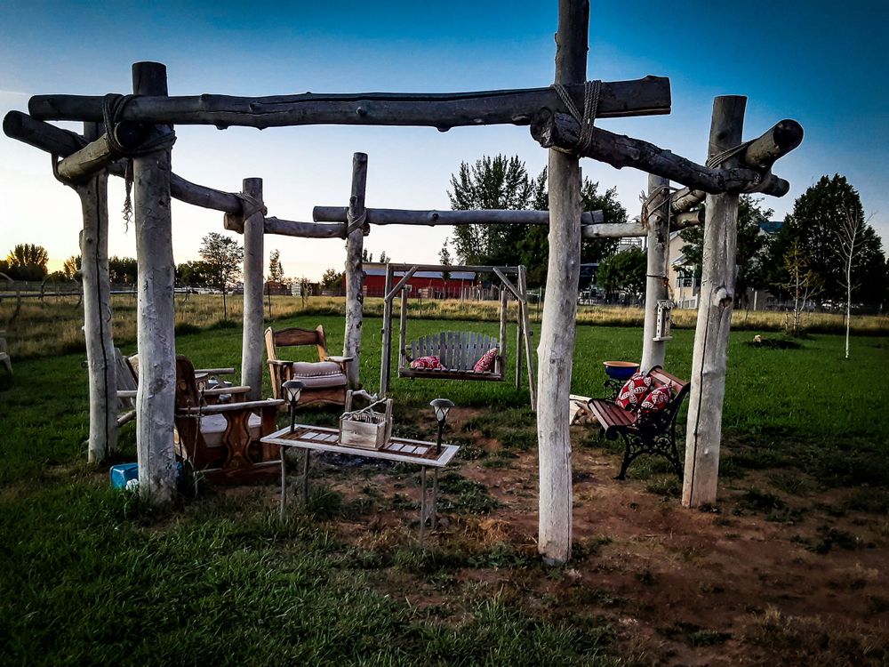 Rustic wooden pergola with bench seating in a peaceful countryside garden setting at dusk.