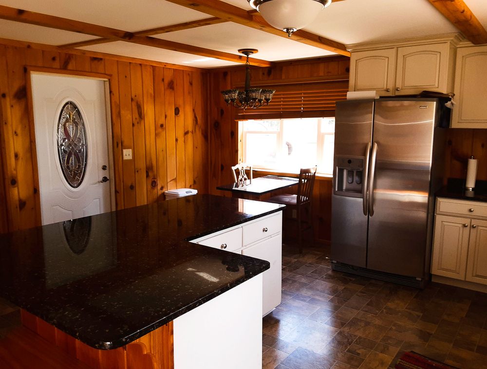Modern kitchen with dark granite countertops, wood paneling, and stainless steel appliances.