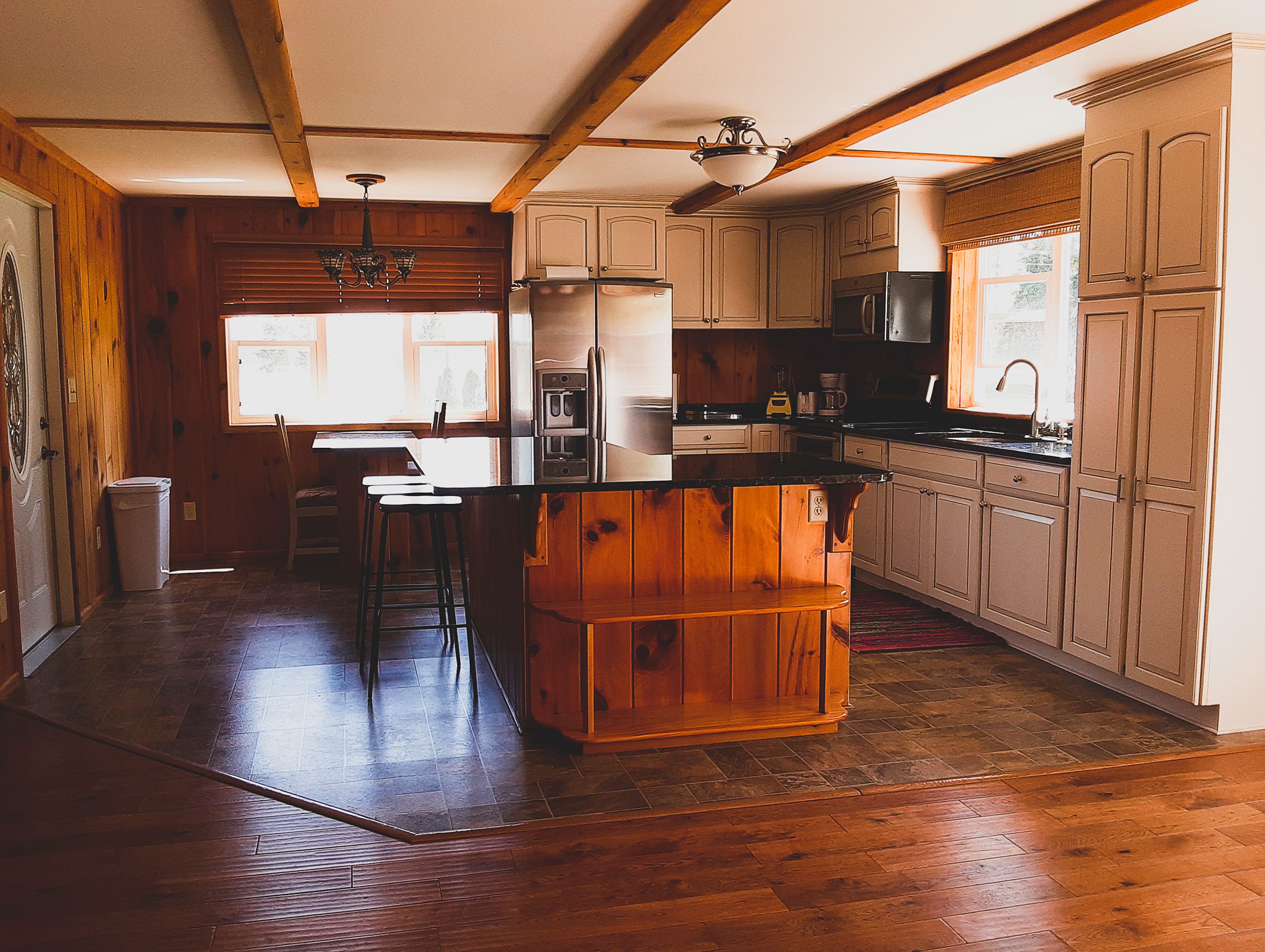 Spacious rustic kitchen with wood beams, hardwood floors and center island.