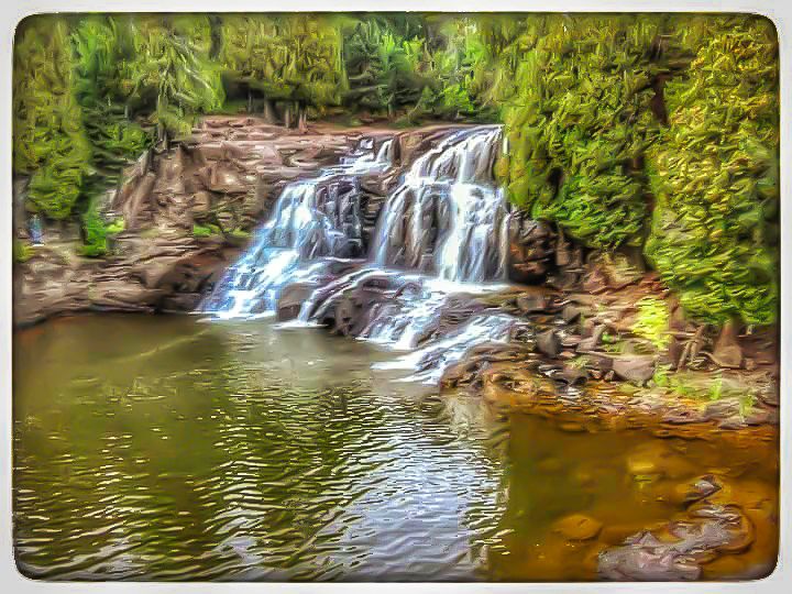 Scenic waterfall cascades down rocky terrain into a peaceful forest pool surrounded by lush greenery.