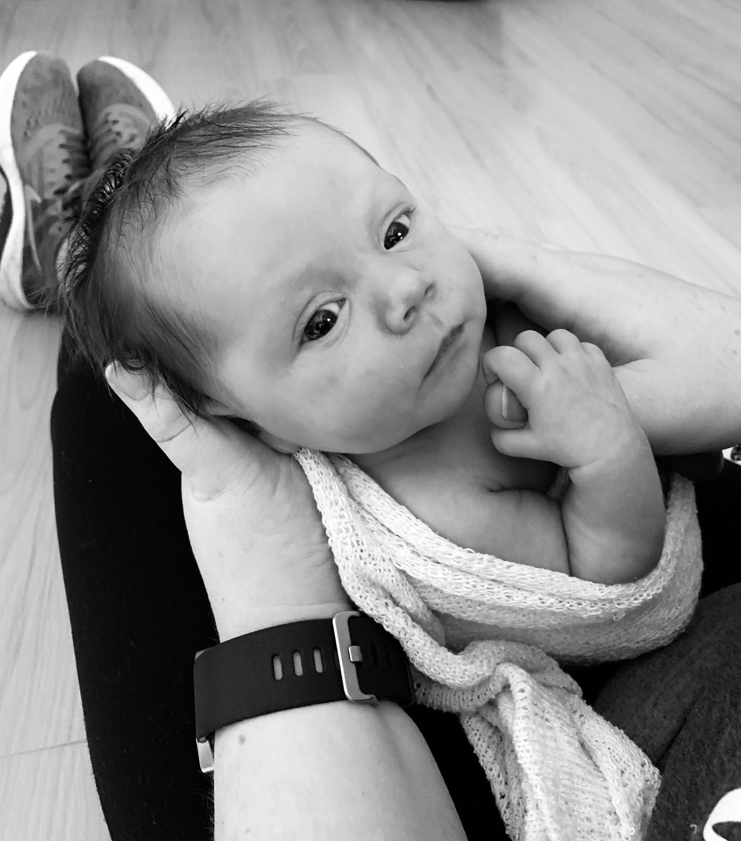 Close-up black and white portrait of infant with hand near face.