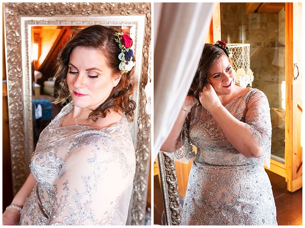 Bride in silver lace gown adjusting hair accessory with floral crown in rustic barn.