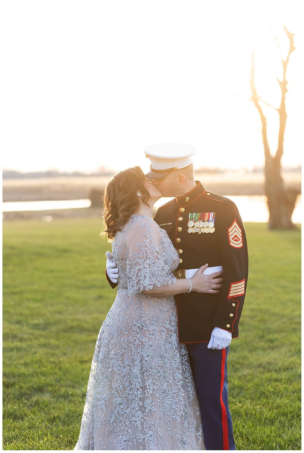 Bride and Marine groom share a kiss at sunset during romantic outdoor military wedding.