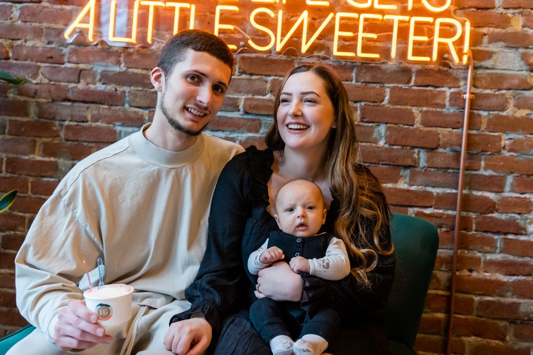 family of 3 laughing together by brick wall