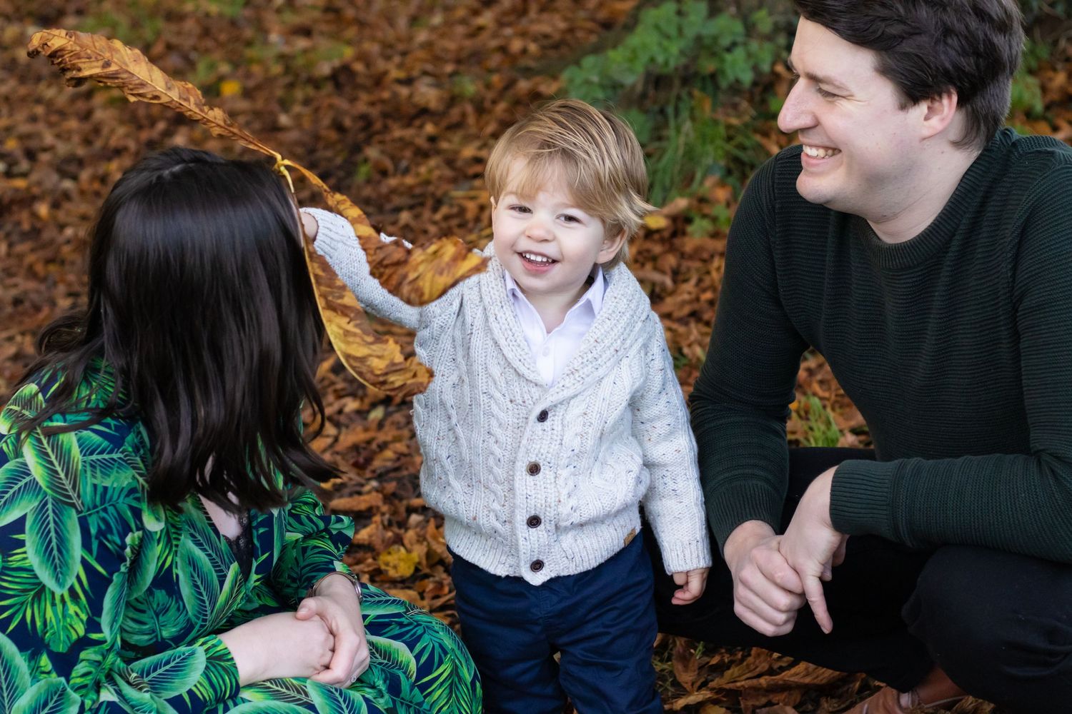 A cheerful family moment captured on fallen autumn leaves in the forest.