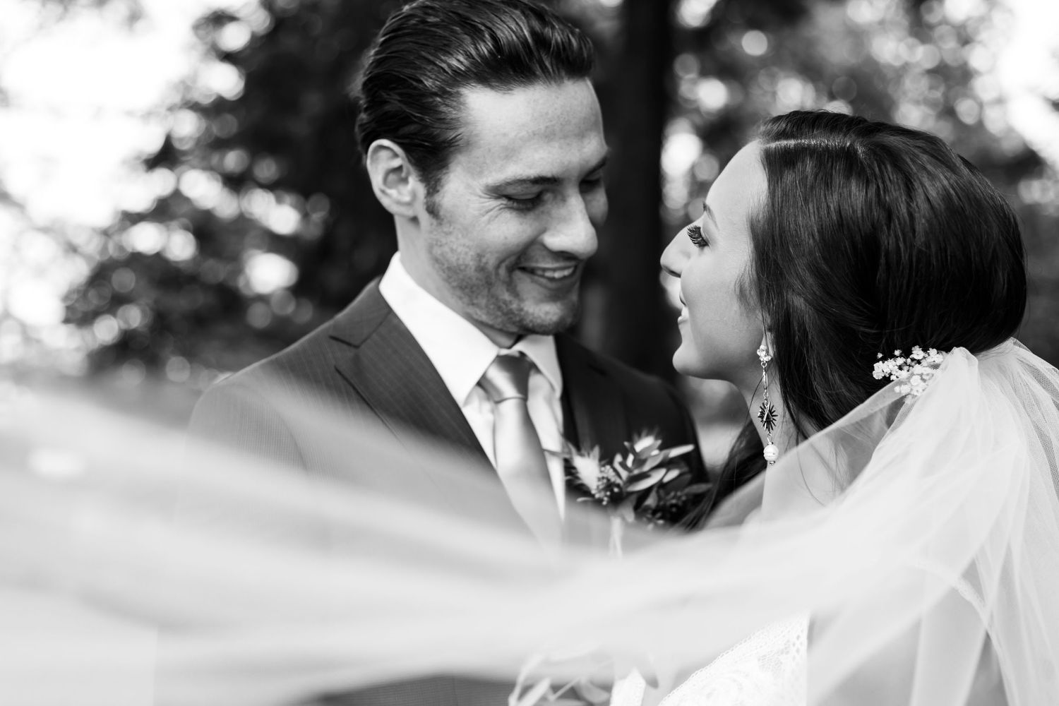 A candid black and white wedding portrait showing laughter and joy between newlyweds.
