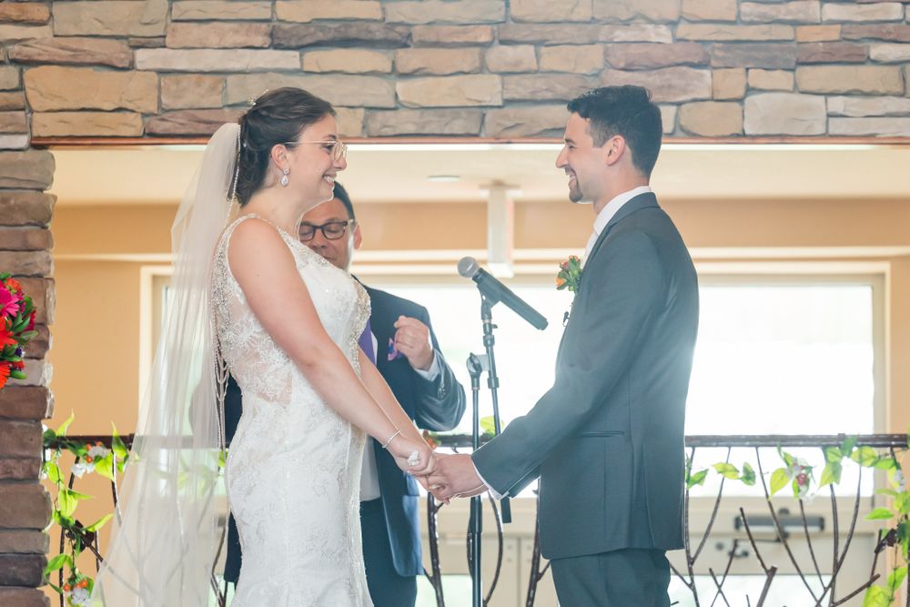 A couple exchanging vows during their wedding ceremony in front of a stone wall backdrop.