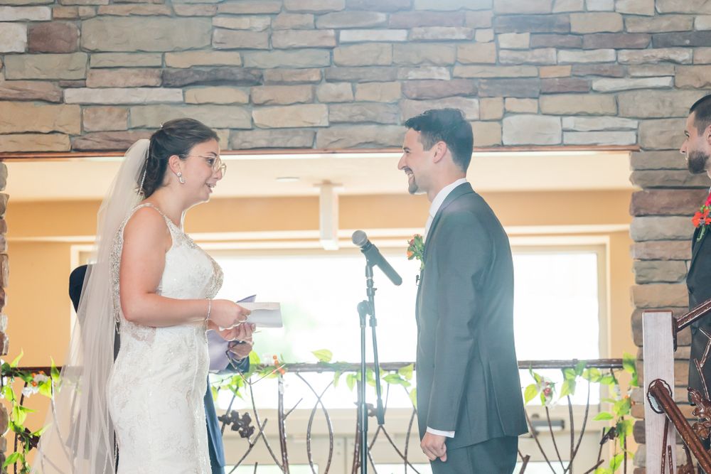 A wedding couple exchanging vows during their ceremony in front of a stone wall.