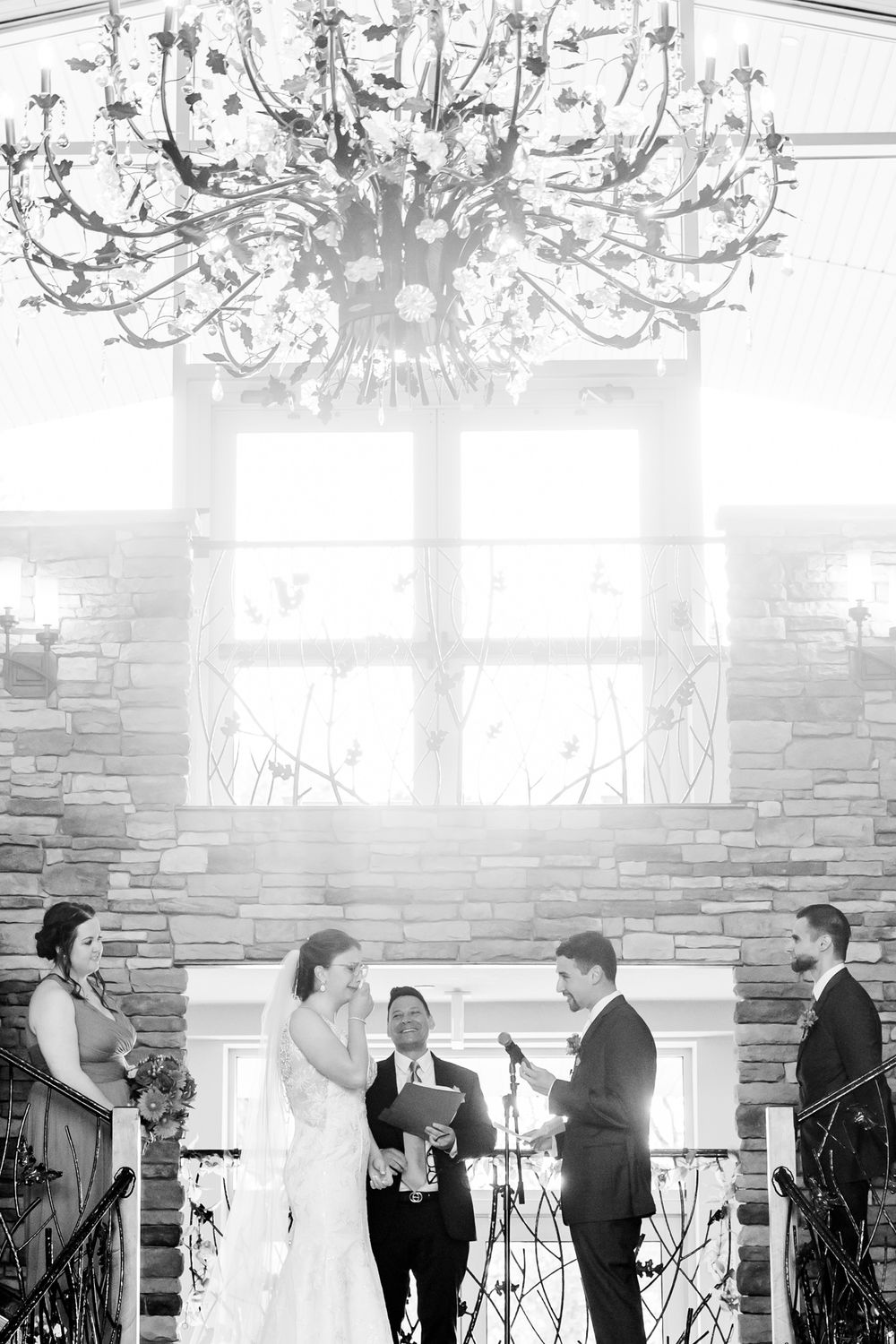 Black and white wedding ceremony photo under an elegant crystal chandelier.