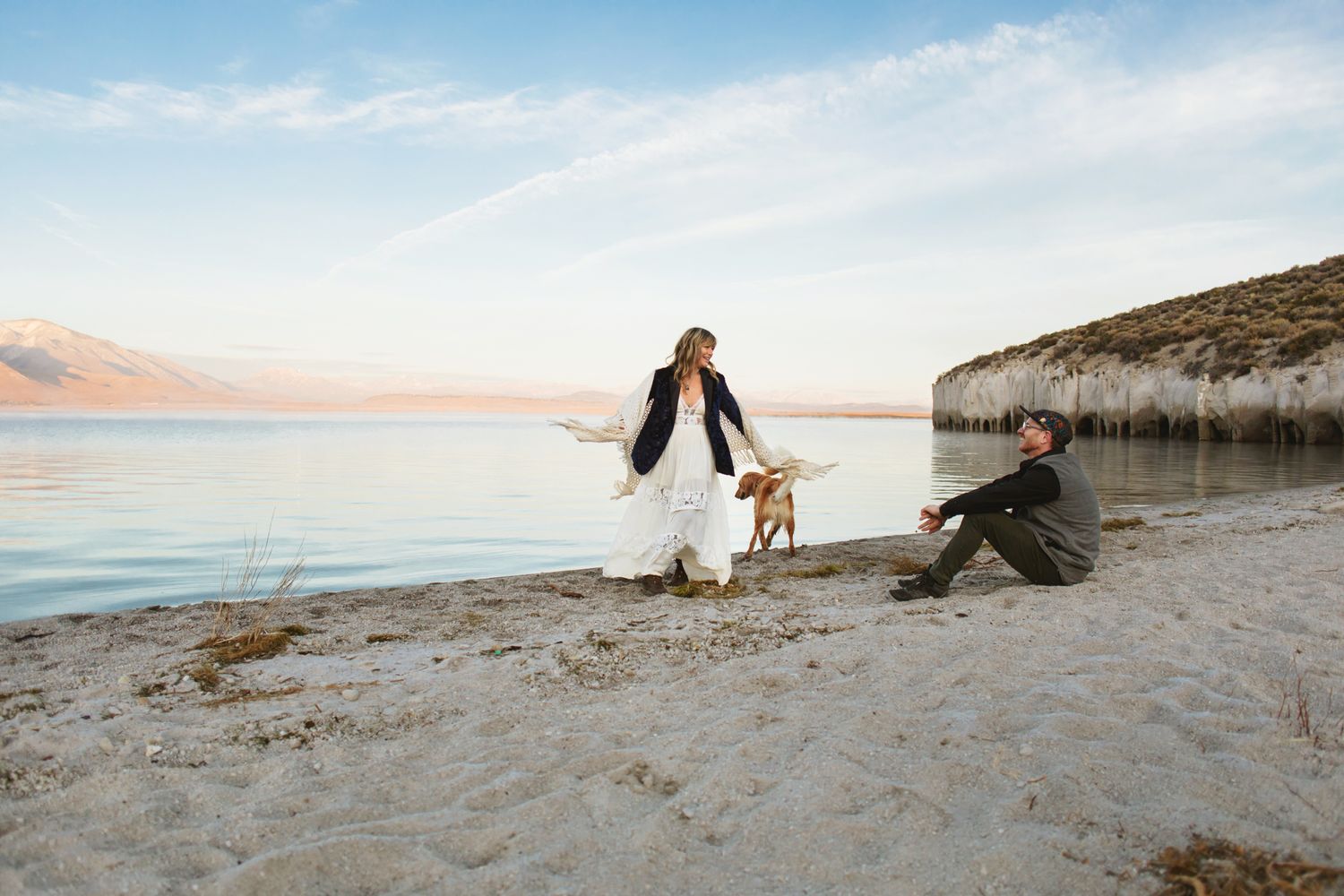 couples photography woman dancing on lake shore while man watches smiling mammoth mountains and Crowley lake columns