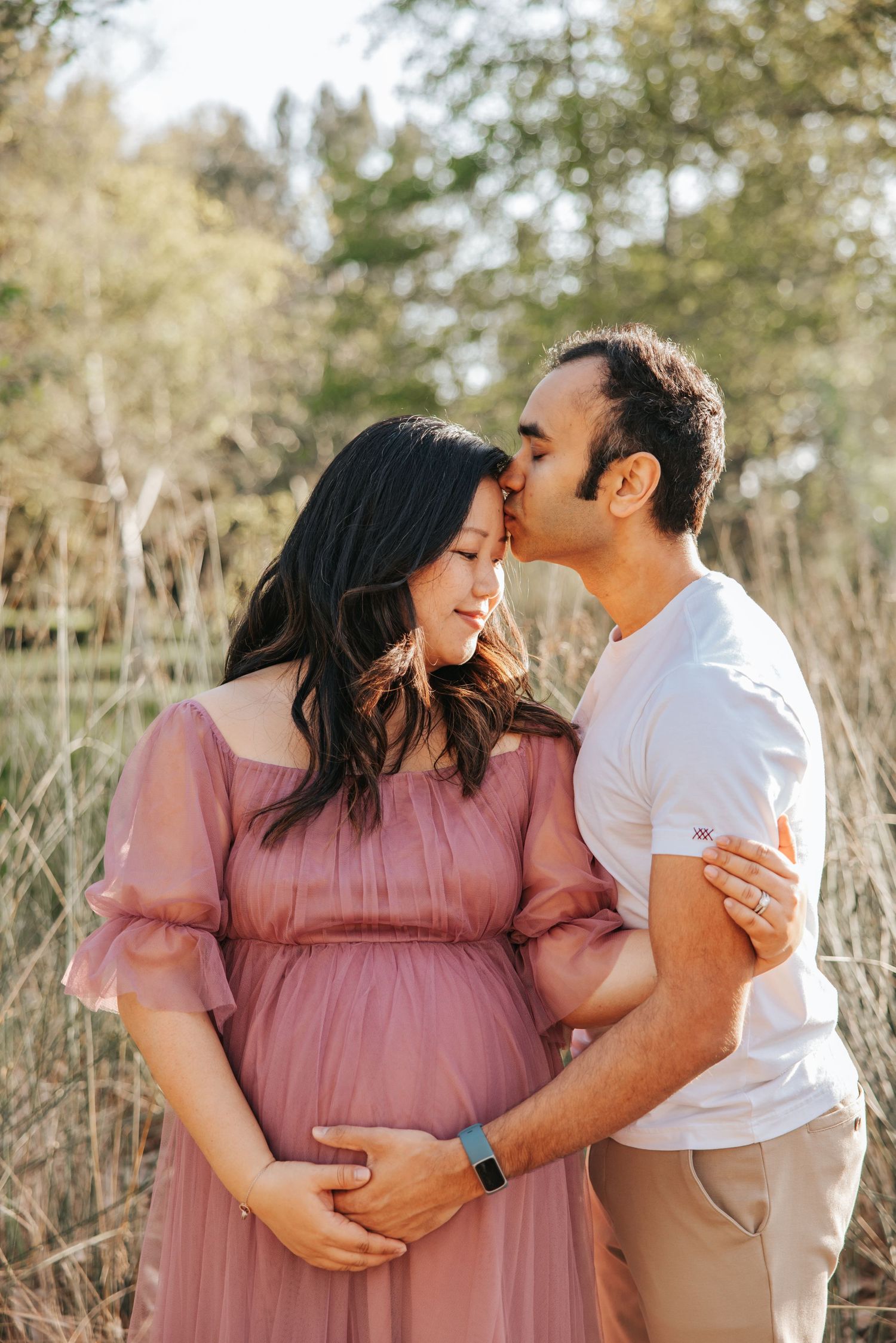 An intimate maternity portrait of a couple sharing a tender moment in natural lighting.