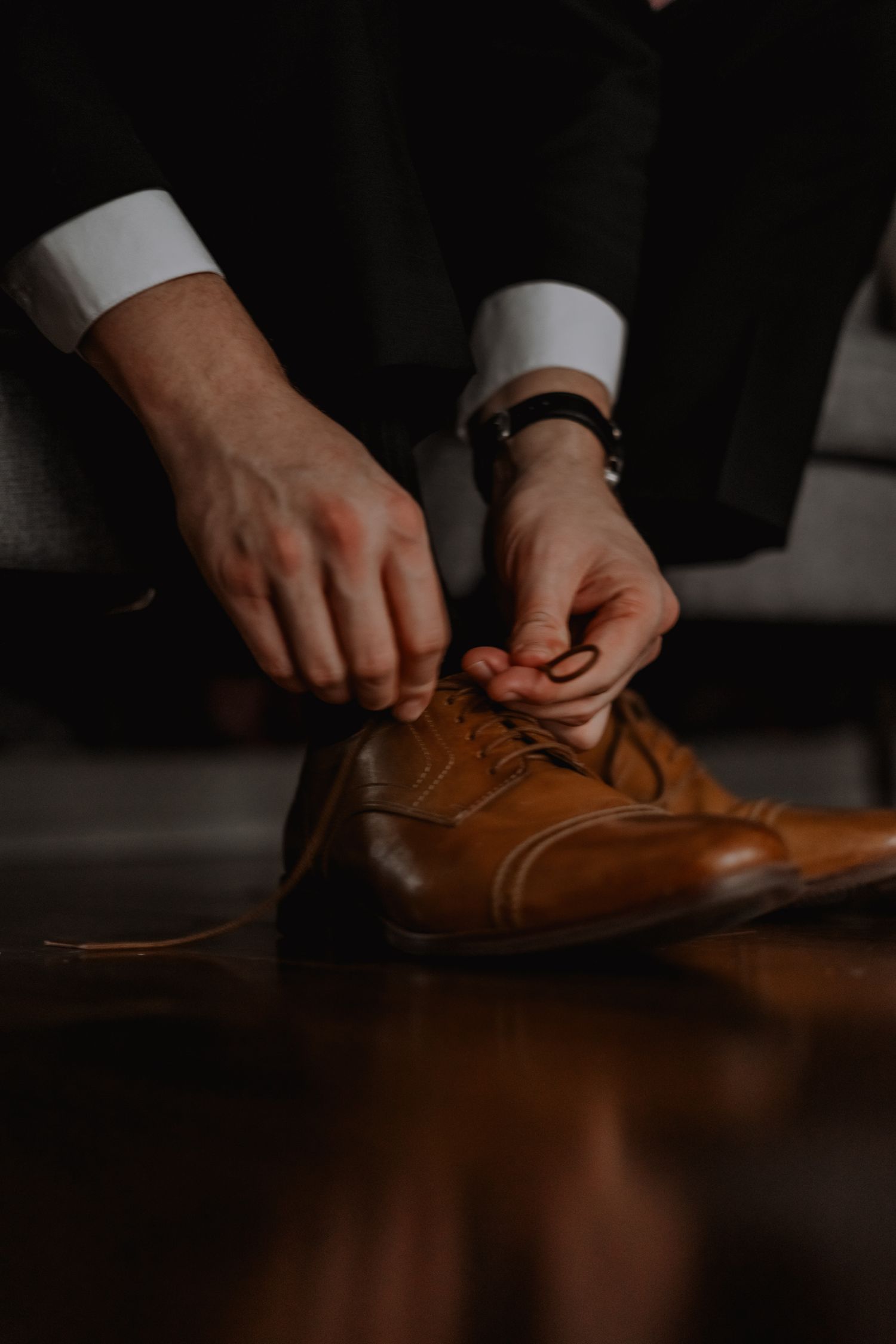 a groom tying the laces of his wedding shoes