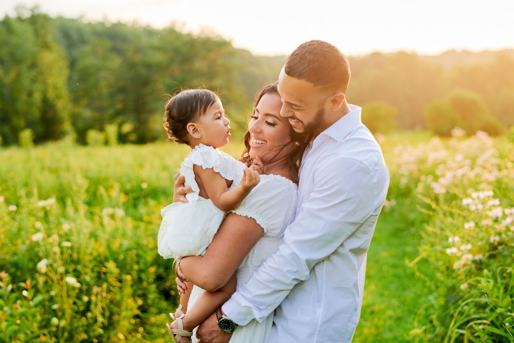 Family embraces together in a sunny meadow filled with wildflowers during golden hour.