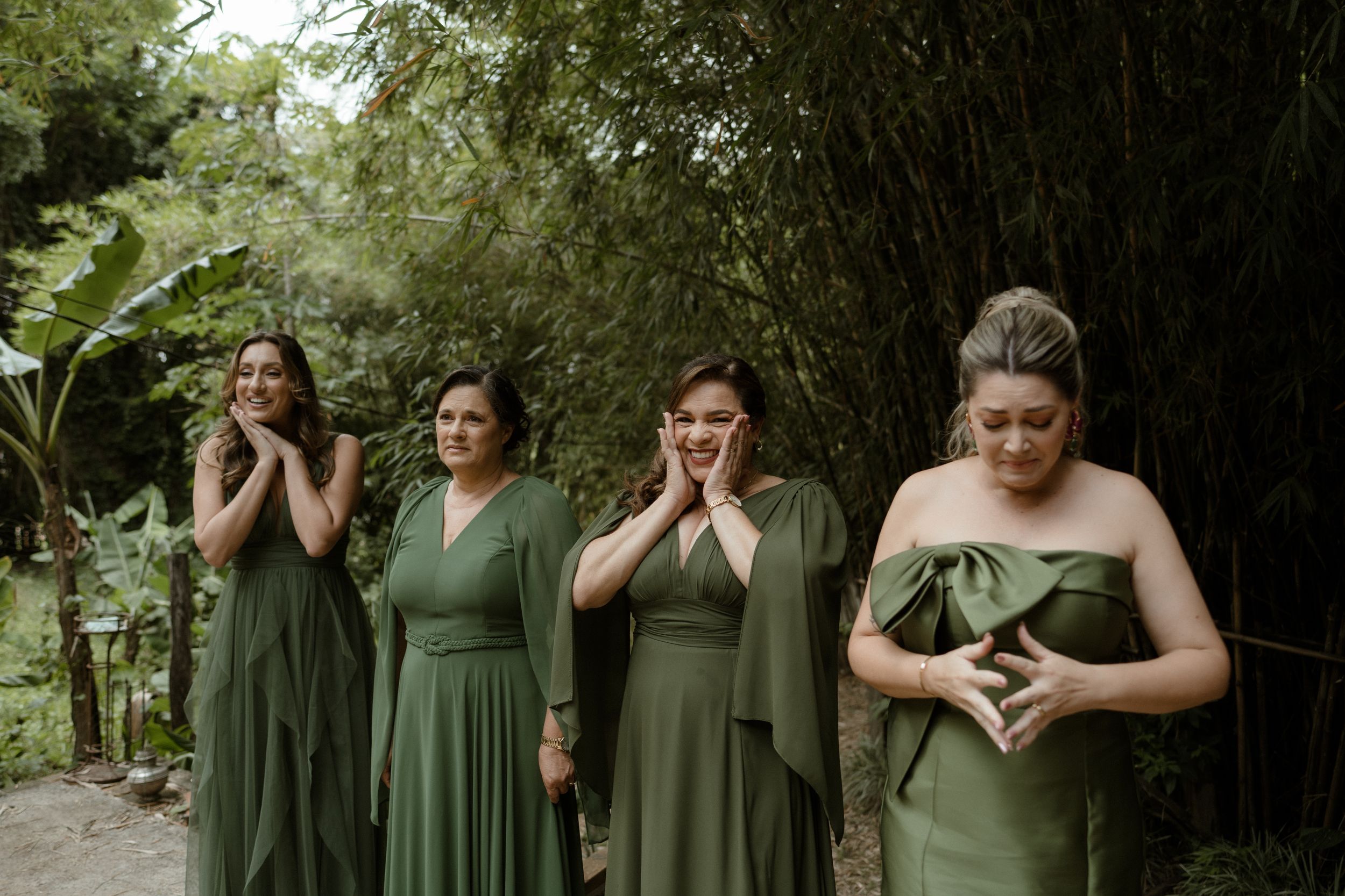 Wedding party in olive green dresses posing outdoors in natural setting.