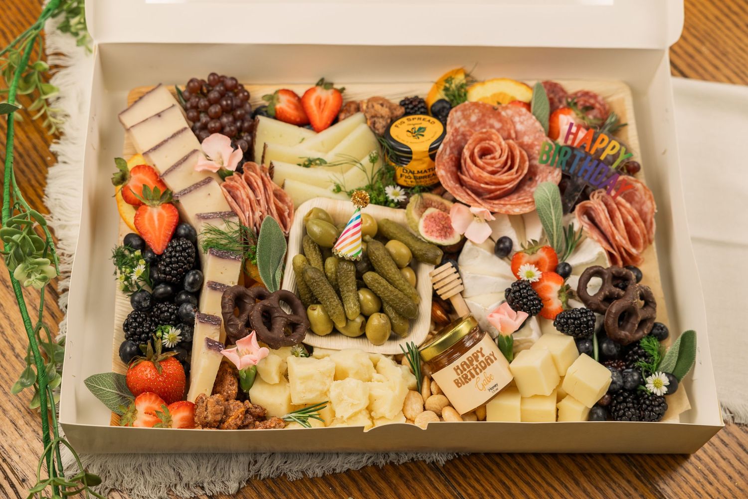 Deluxe charcuterie box filled with cured meats, cheeses, fruits, and pickled vegetables.