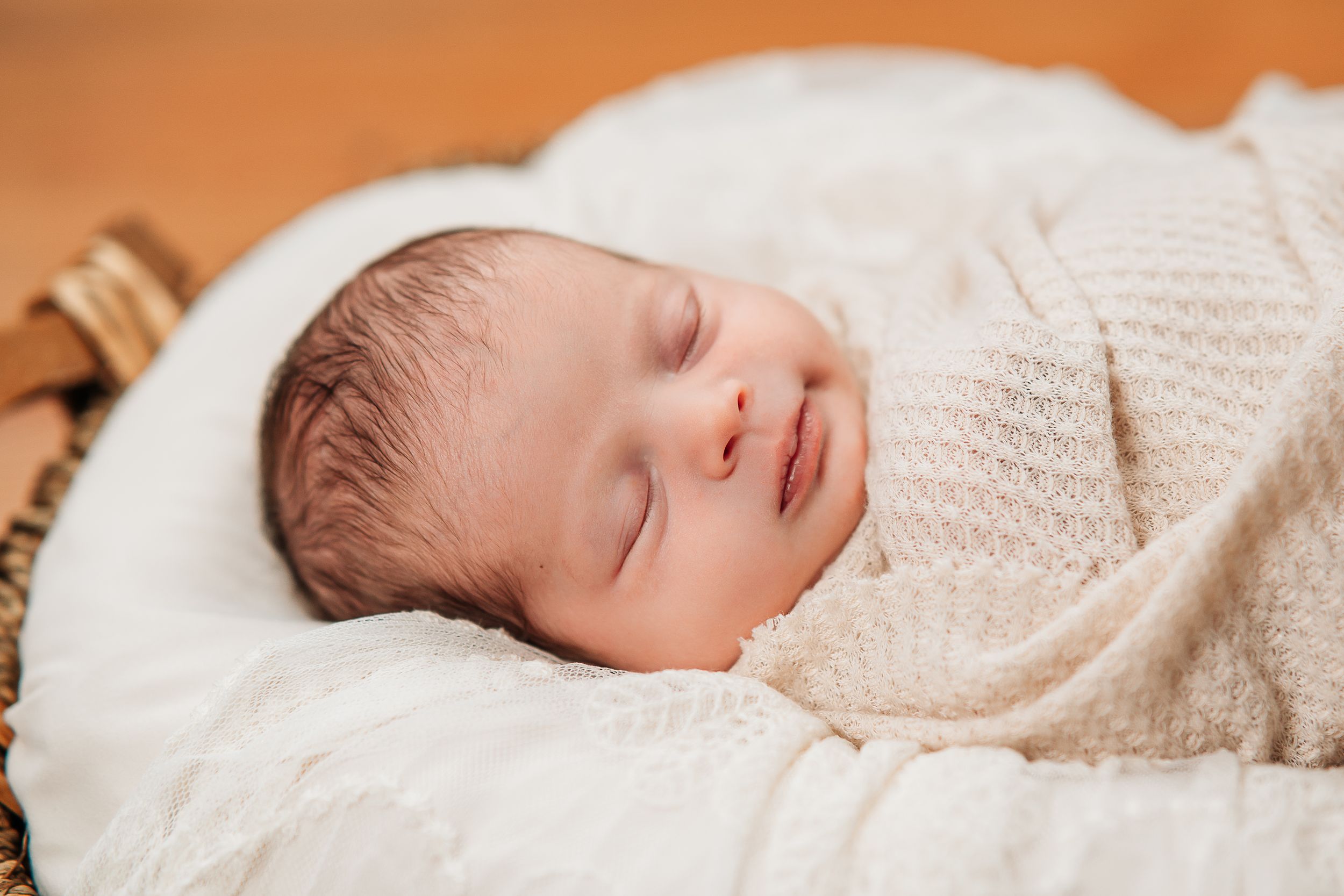 Serene newborn baby sleeping peacefully wrapped in soft white knitted blanket.