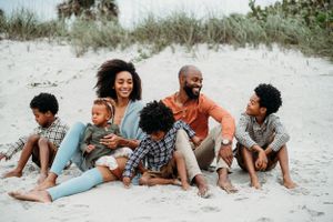 Family relaxing together on sandy beach during golden hour.