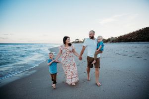 Family enjoying a playful moment together while walking along the beach at sunset.