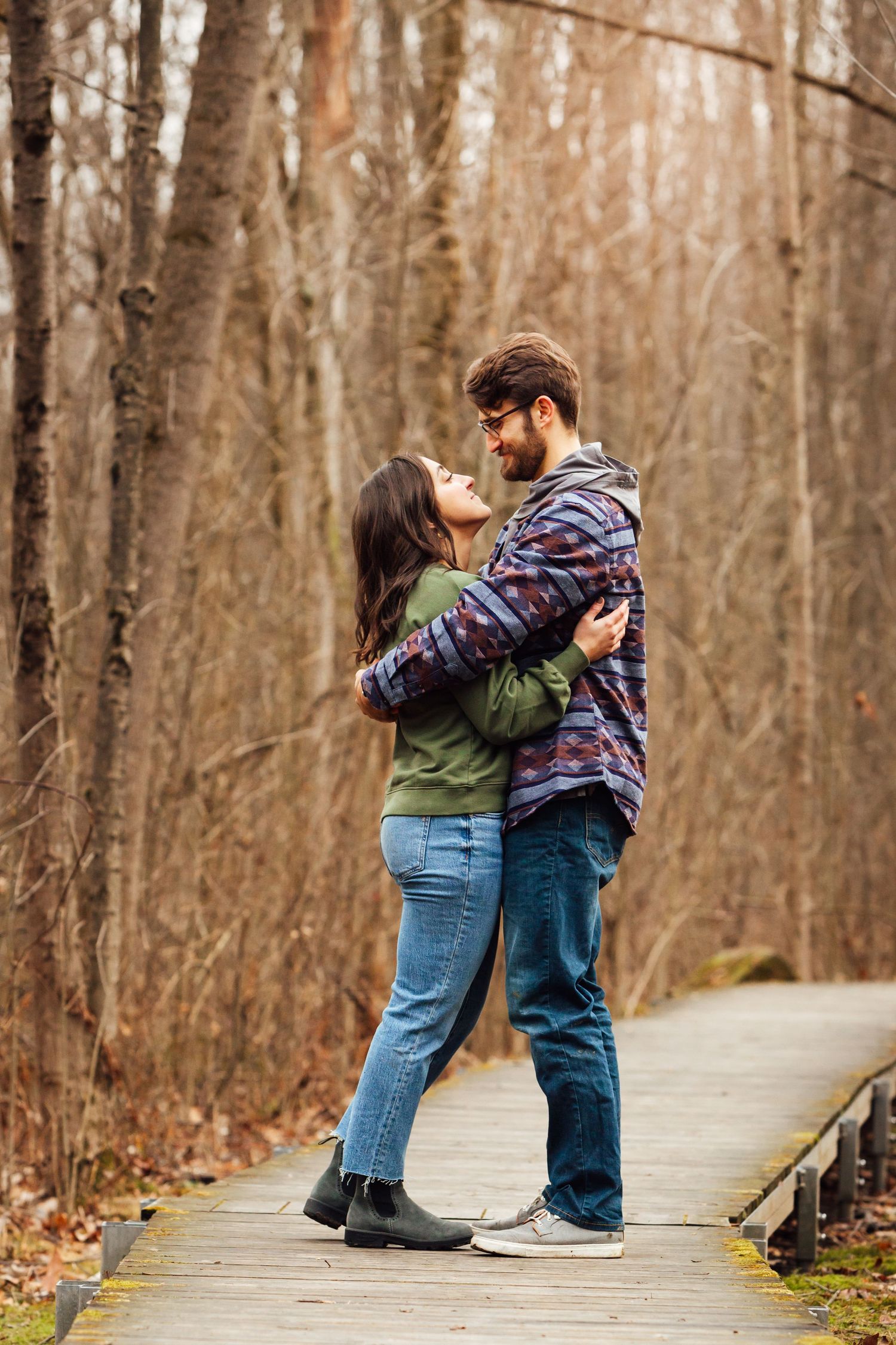casual couples embrace on boardwalk with sun through trees