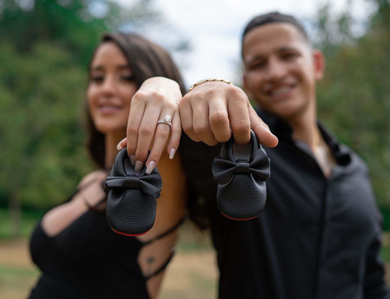 Couple showing joy while holding new born shoes outdoors.
